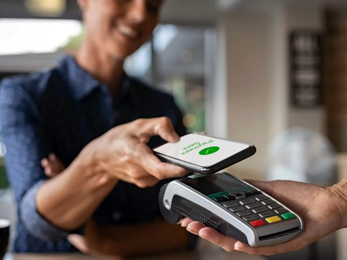 Customer taps a phone on a merchant payment terminal to redeem a mobile voucher