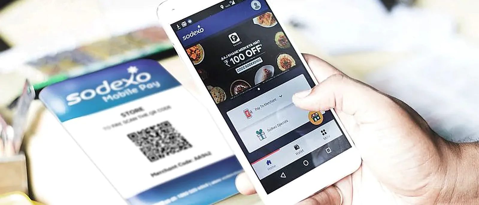 Customer paying with the Sodexo Mobile Pay app in front of a merchant QR code stand